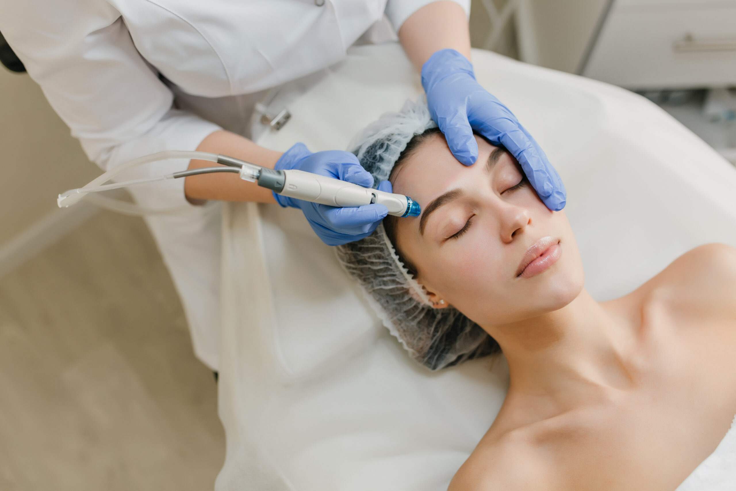 View from above rejuvenation of beautiful woman enjoying cosmetology procedures in beauty salon. Dermatology, hands in blue glows, healthcare, therapy, botox. RF-Microneedling Kempten